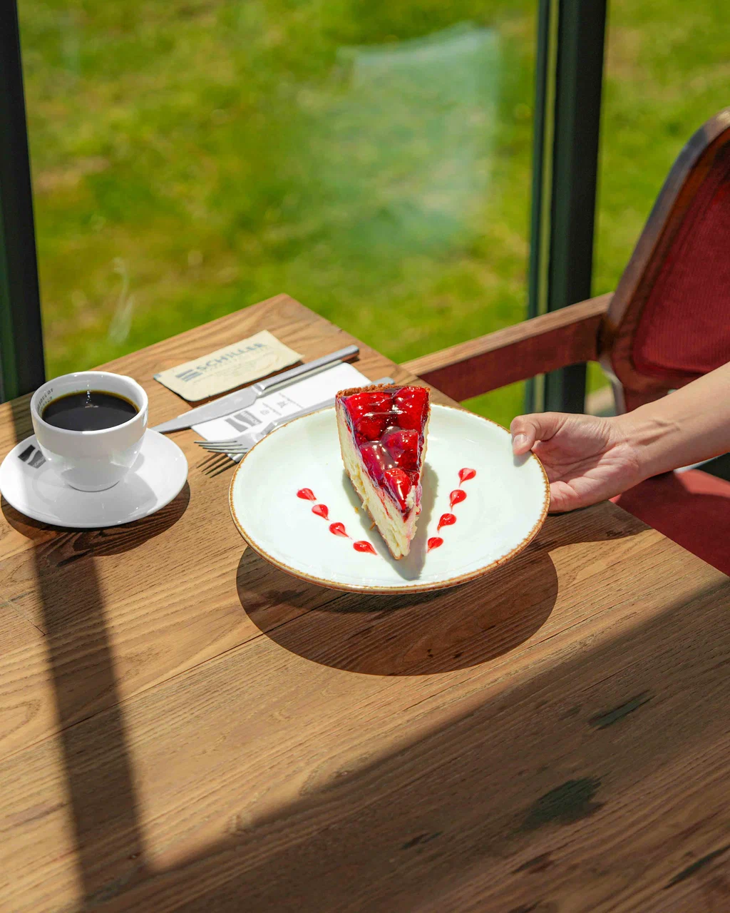 Bahçe manzaralı masada frambuazlı cheesecake ve filtre kahve